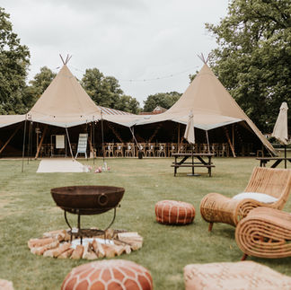 Outdoor firepit and chill out furniture at tipi wedding in a field in the summer