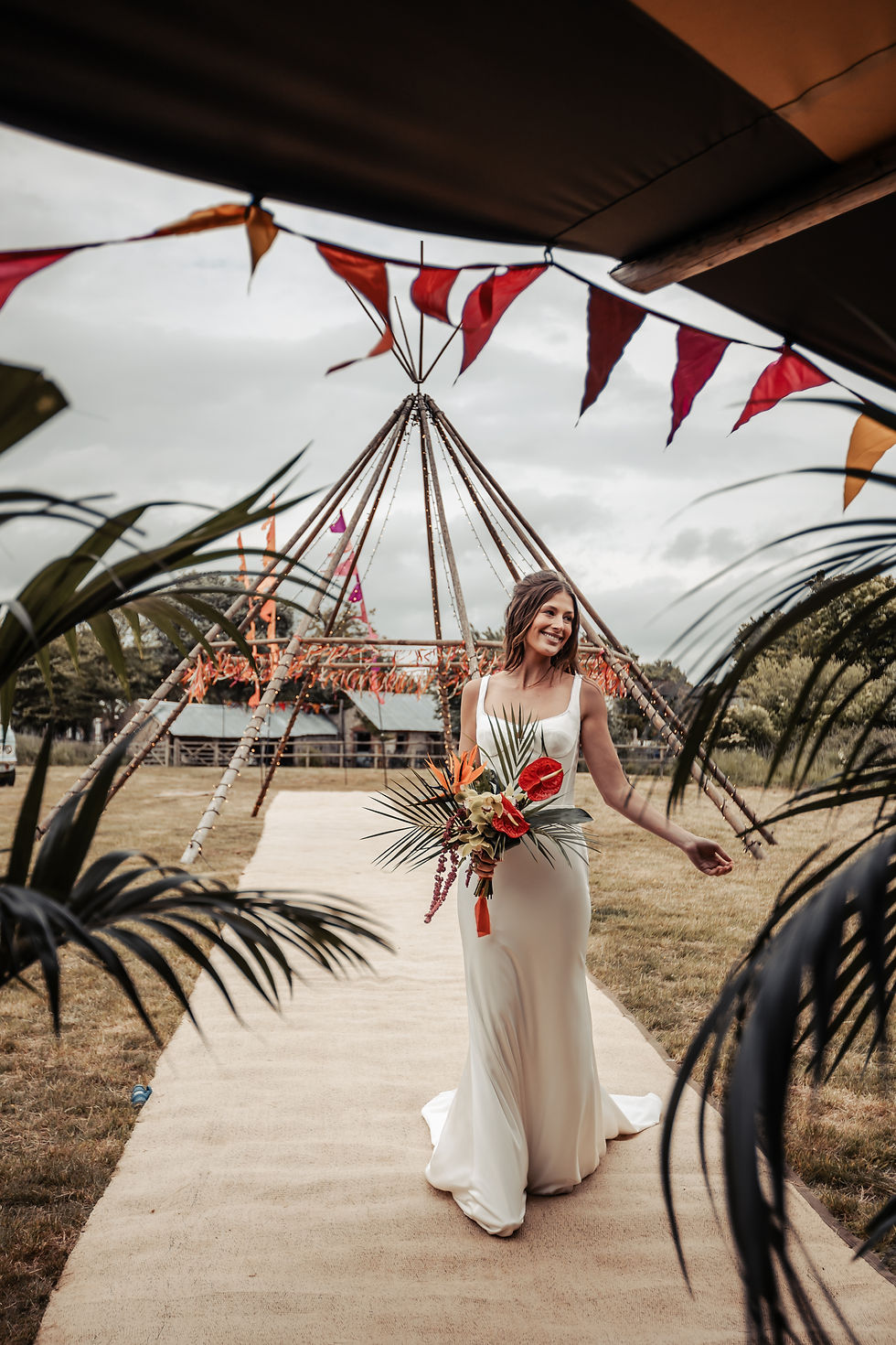 Bride at an outdoor tipi festival wedding with tipis, colourful bunting and festival flags.