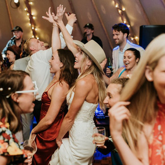 bride and friends dancing at tipi wedding in cowgirl hats