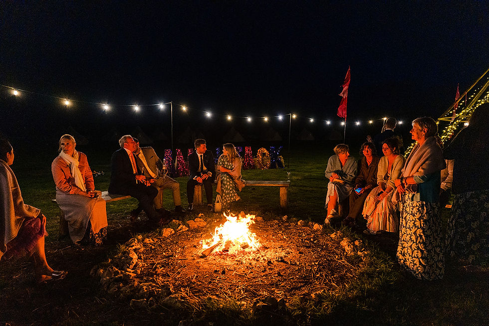 Wedding guests gather around a campfire 