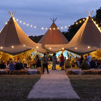Tipi wedding in a field with festoon lights