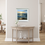 Thumbnail: Embrace of light framed coastal seascape print by Ben Goymour hanging above a light wood hallway table with simple décor.