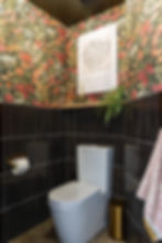 Modern bathroom with floral wallpaper and black tile.