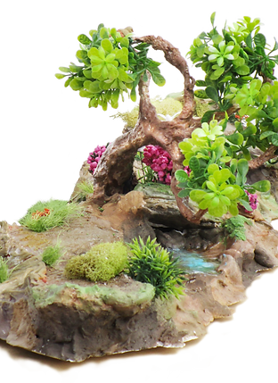 Rustic home decor that sets a scene and tells a story as your tablescape. Whimsical Rosey Bloom Lagoon makes a unique accent piece that will instantly bring the outside into your space. Faux mini tree, faux water effect & lust foilage. Oasiscapes Home Decor adds a little drama to your space.