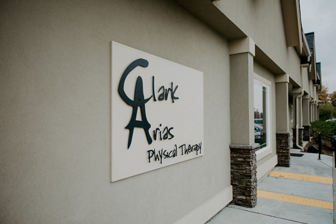 A close-up of a sign that says "Clark-Arias Physical Therapy" on the outside of a building.