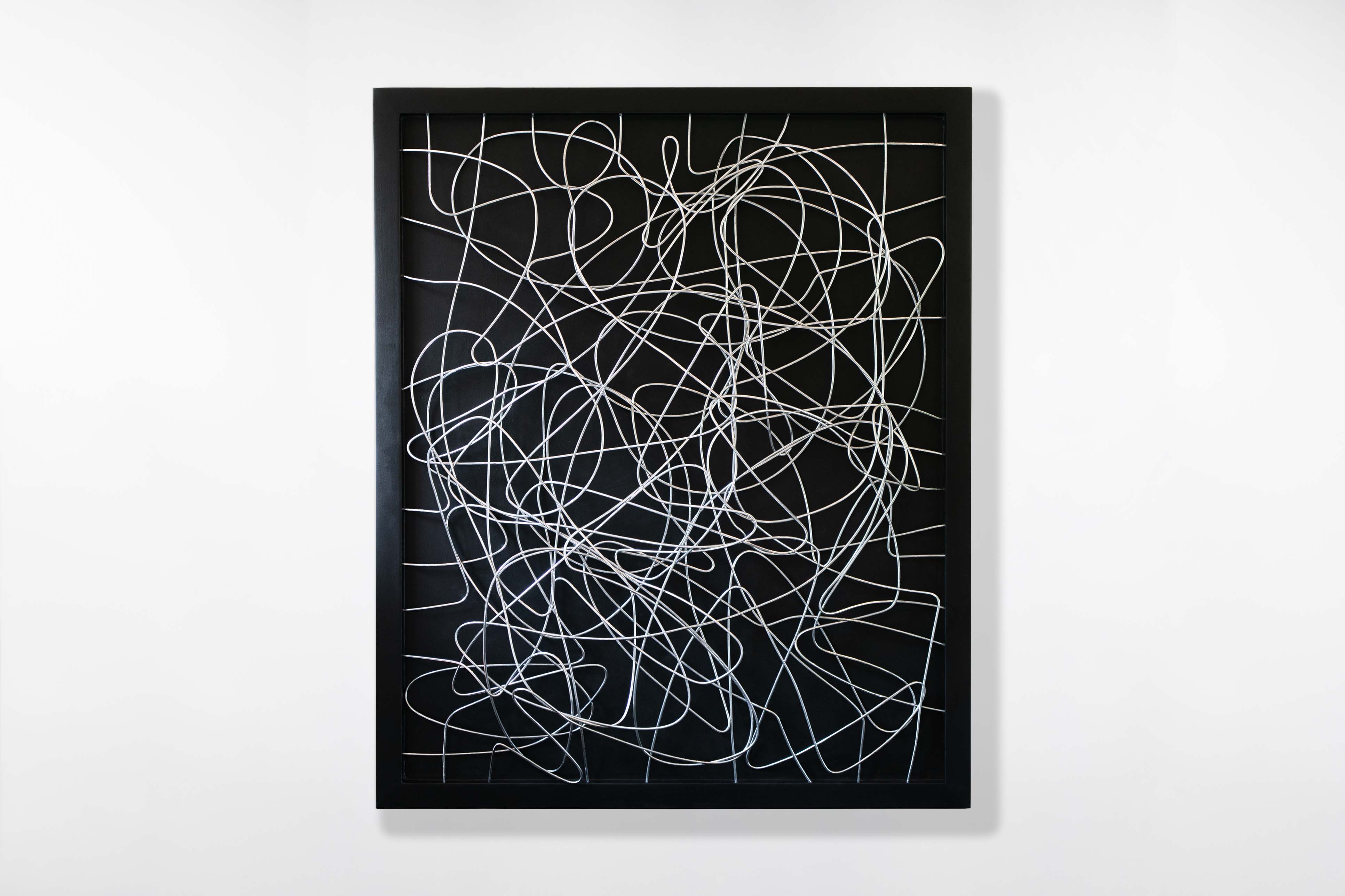 Large framed wall artwork by artist Cameron Hunt featuring an intricate network of looping chrome wires on a deep black background, creating an abstract tangled pattern.