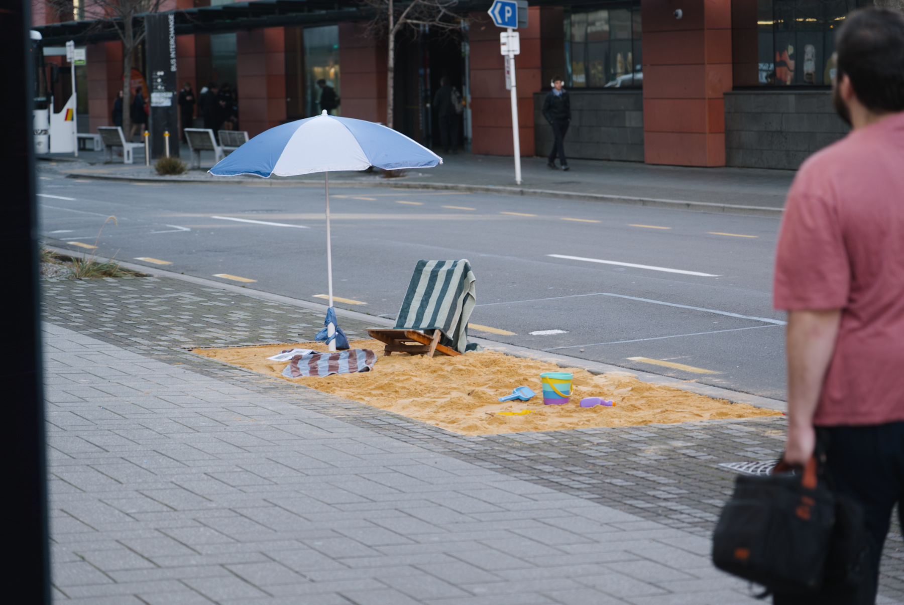 A public beach installation in the middle of the city complete with beach umbrella, beach chairs and towel by street artist Cameron Hunt.
