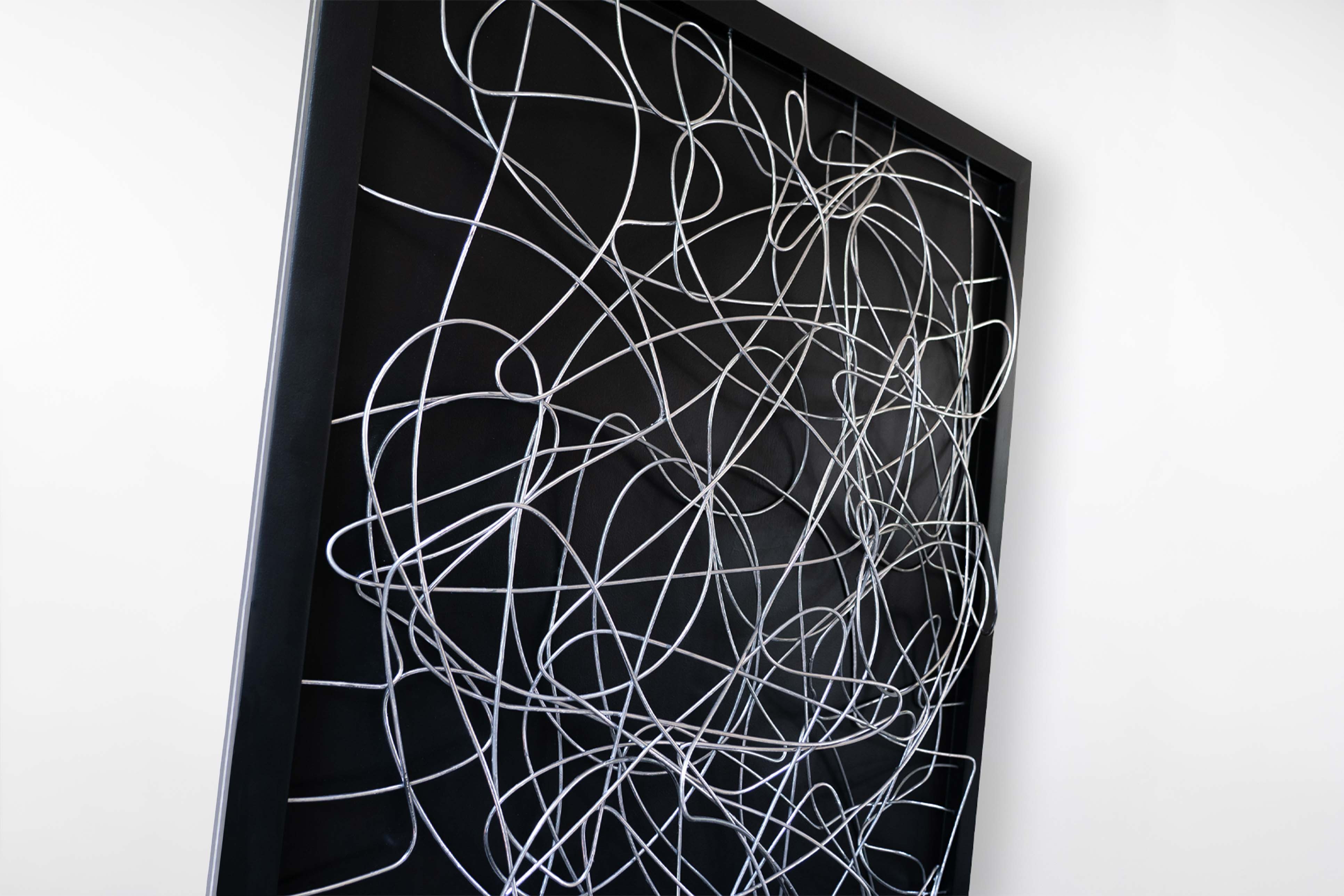 Side angle view of the black-framed artwork by Cameron Hunt with chrome tangled wires, highlighting the depth and three-dimensional texture of the sculpture.