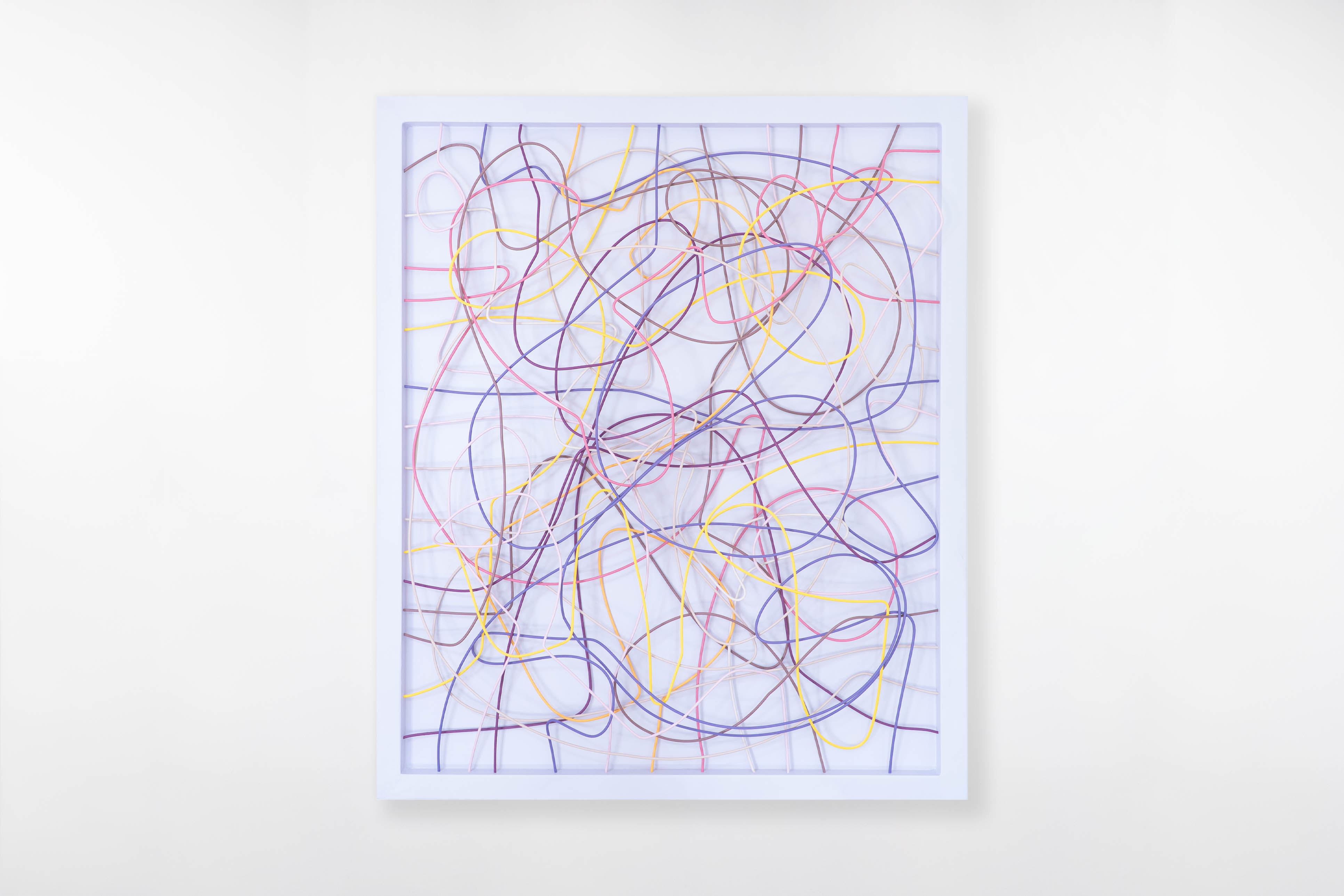 Front view of artist Cameron Hunt’s wall sculpture with pastel-colored wires in pink, yellow, purple, peach and brown, layered within a clean white frame.