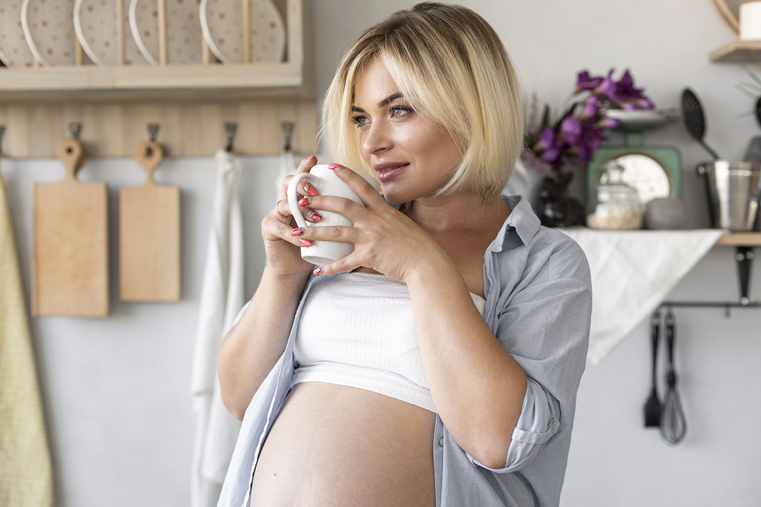Pregnant woman drinking pure water from a modern faucet