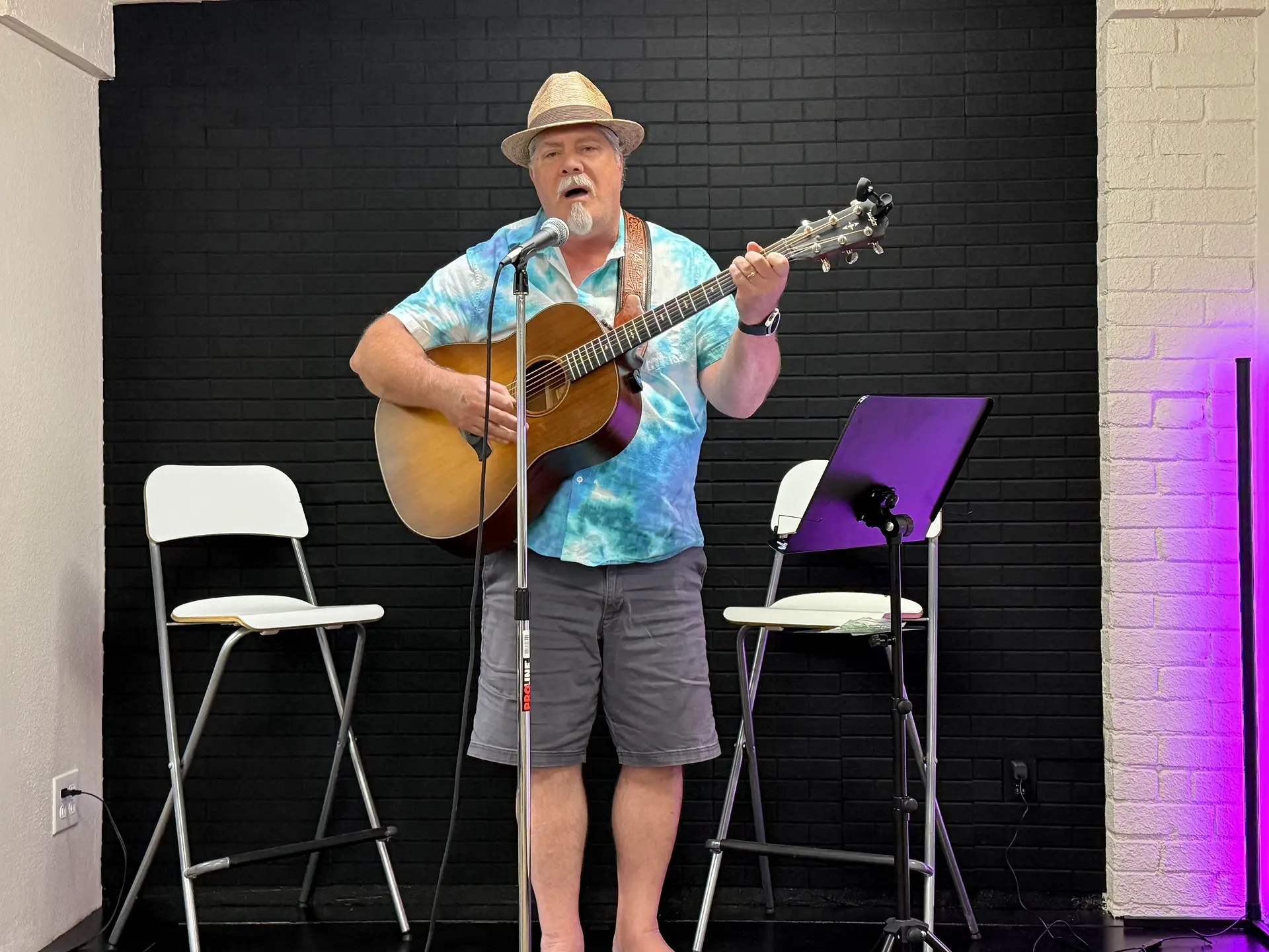 Man holding a guitar singing at Emmett Hayes Voice Studio