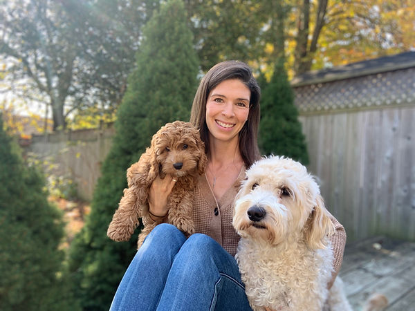 Robyn Murphy certified hypnotherapist with a small brown cockapoo and a golden doodle against a treed background