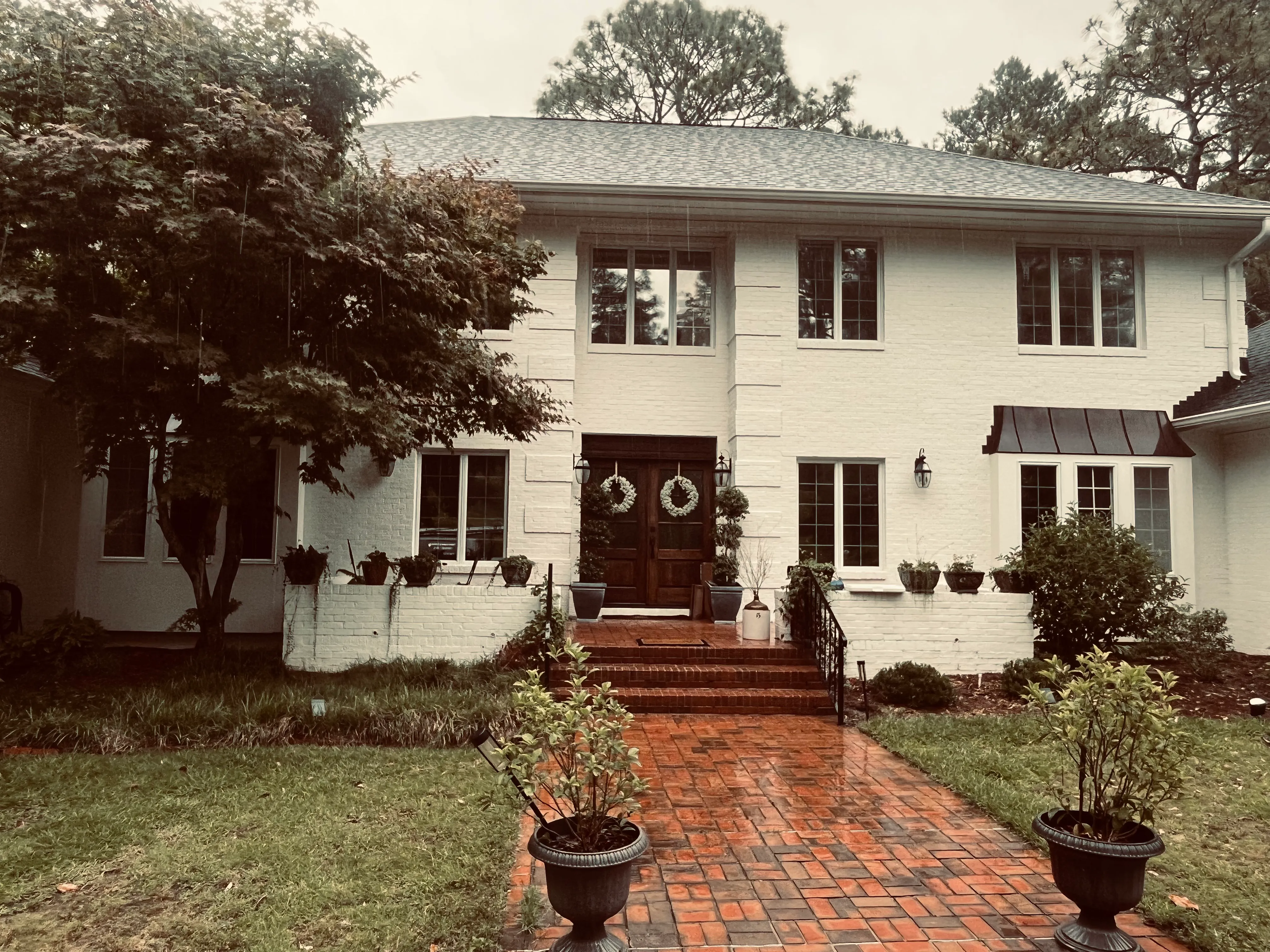 Large two-story white home with clean red brick steps.