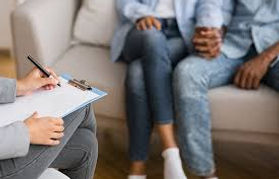 Therapist taking notes during a counseling session with client, representing couples therapy and mental health support