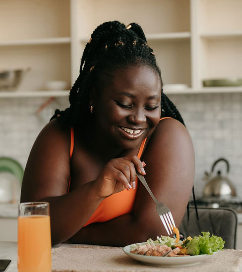 Femme presenting black human smiling and eating a healthy salad.jpg