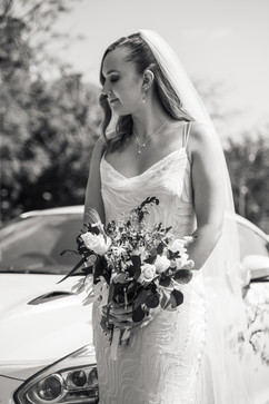 Beautiful young bride posing next to white sports car as she arrives at her wedding at the Sun Pavilion Harrogate
