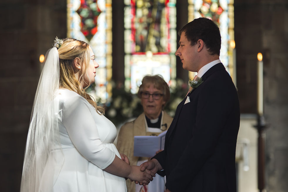 Beam of sunlight falls across bride's face during vows ceremony at a church wedding near Stoke during Covid
