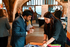 Guests arriving for conference in medieval hall chatting.