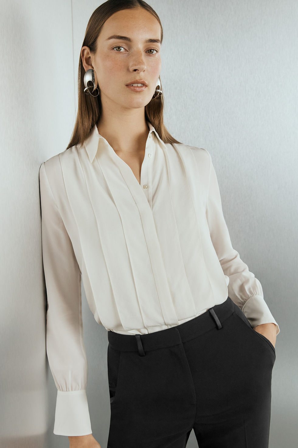 Woman in cream pleated blouse and black pants
