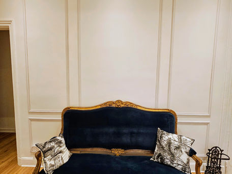 Artisan Anka Paris posant des moulures ornementales au plafond d'un salon. Anka, l'art de la décoration intérieure avec moulures à Paris.