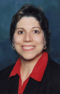 Smiling woman with dark hair, red shirt, and black blazer.