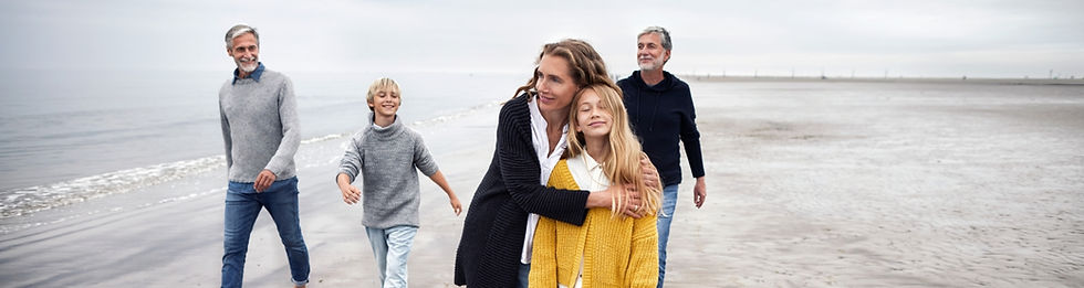 Multi-generational family walking on a cloudy beach