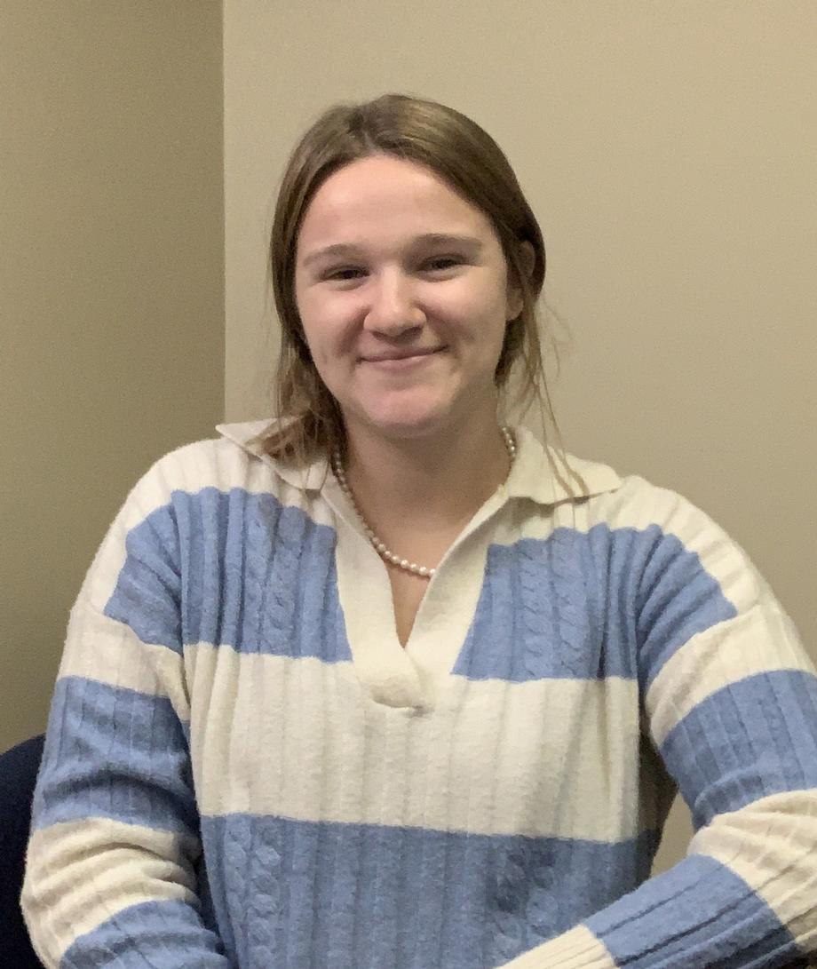 Smiling team member in a blue and white striped sweater.