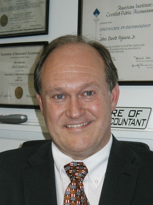 Smiling man in a suit in front of framed certificates