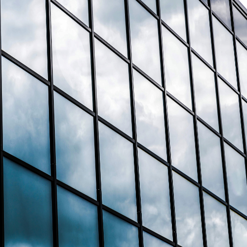 Modern glass skyscraper reflecting clouds and sky