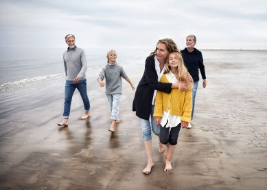 Multigenerational family walking on a sandy beach.