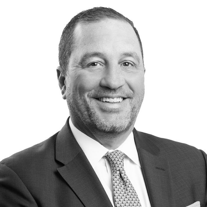 Smiling man in a suit for the Our Team page.