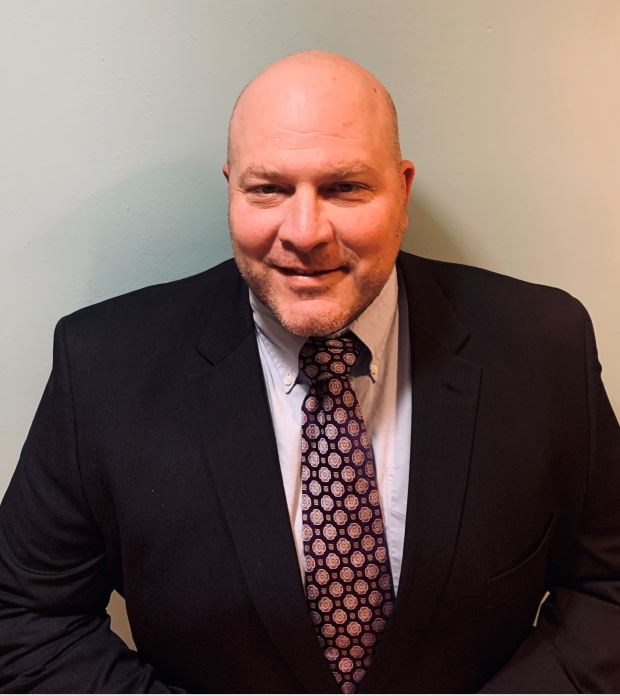 Smiling professional man in a suit and patterned tie.