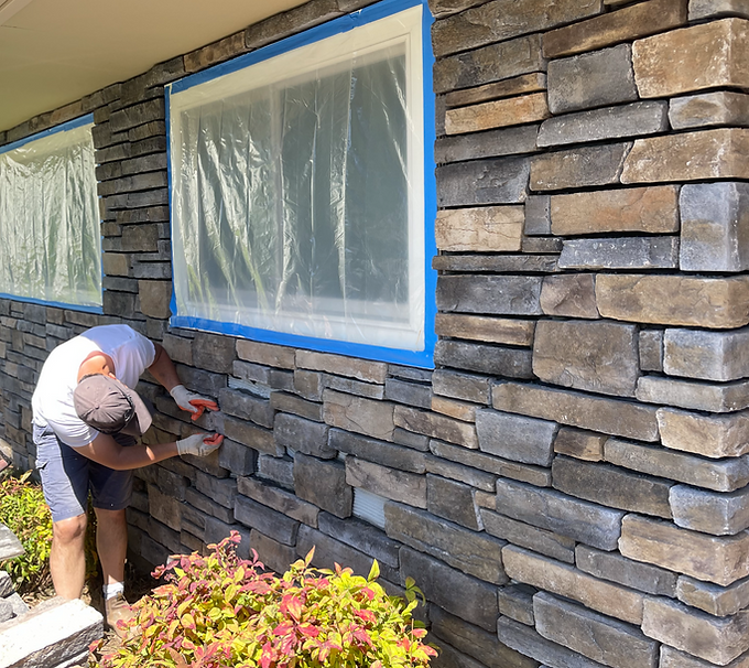 A man working on custom stone masonry on the exterior of a house.