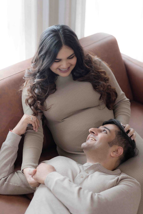 expecting couple posing on couch 