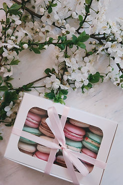 Boîte de Macaron fermée d'un ruban. Sous des fleurs blanche.