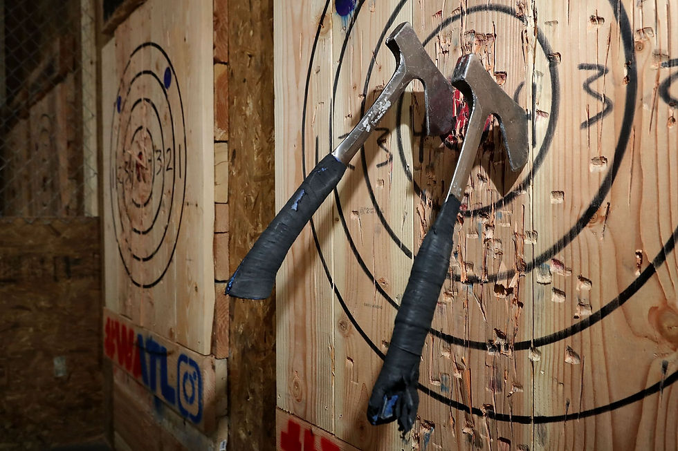 Two axes embedded in a wooden target with black circles. Visible text: "HWATL" and Instagram logo. Rustic wood setting.