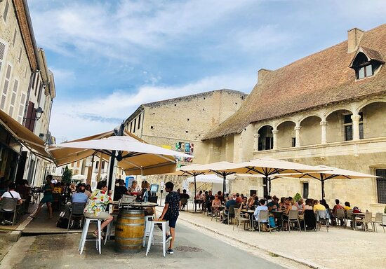 Bistros and bars bustling with activity near the historic Henry IV castle in Nérac, showcasing the vibrant local food and drink scene.