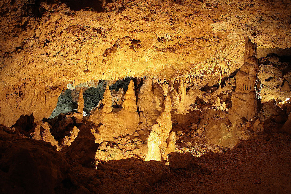 Illuminated cave interior with stalactites and stalagmites. The earthy tones create a warm, mysterious atmosphere in the underground setting.