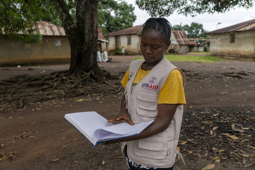 Alice Togbah, a community health worker, looks at a log of residents she provides health services to, in Bong County, Liberia, Saturday, June 14, 2025.(AP Photo/Annie Risemberg)