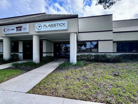 Exterior view of Flagstick Golf Performance in Boynton Beach, Florida, showing the entrance with the company sign above the door.