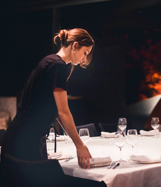 A server laying a table in a candlelit dining room before service