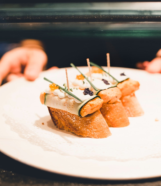 A chef's hands setting canapés onto a white plate
