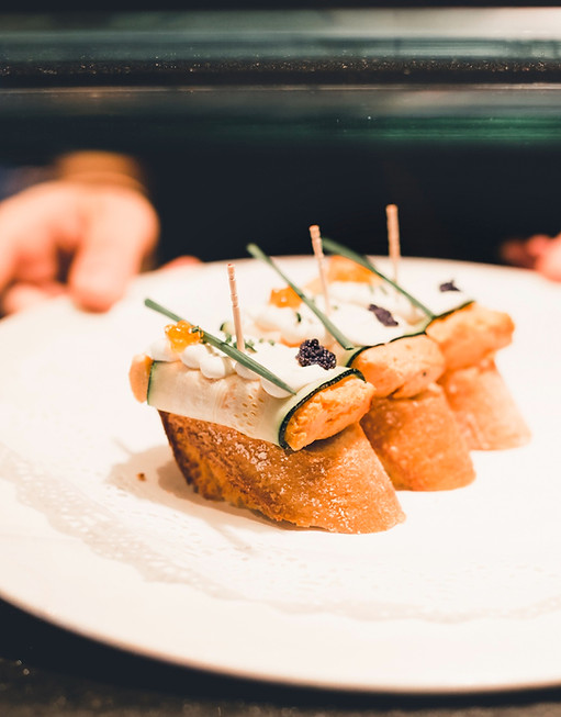 A chef's hands setting canapés onto a white plate