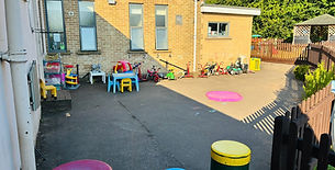 Outdoor play area with toys, tables, and colourful bollards