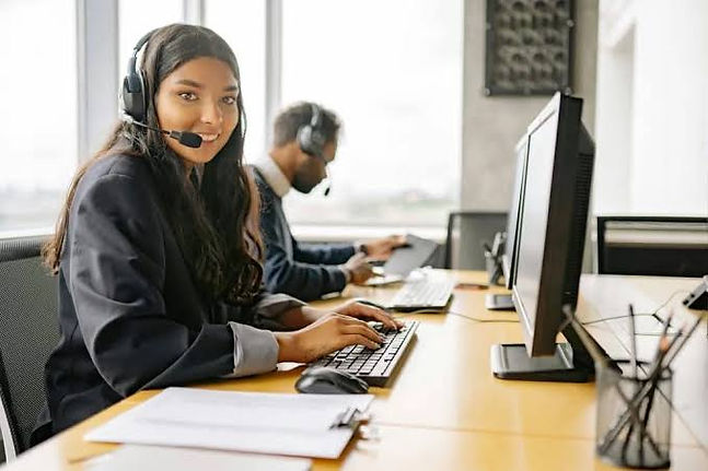 Support agent with headset working at a computer desk.