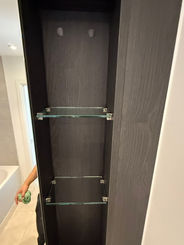 Tall, built-in dark cabinet with two glass shelves