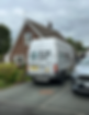 Side view of a white DG NW Plumbing & Heating branded van parked on a residential street