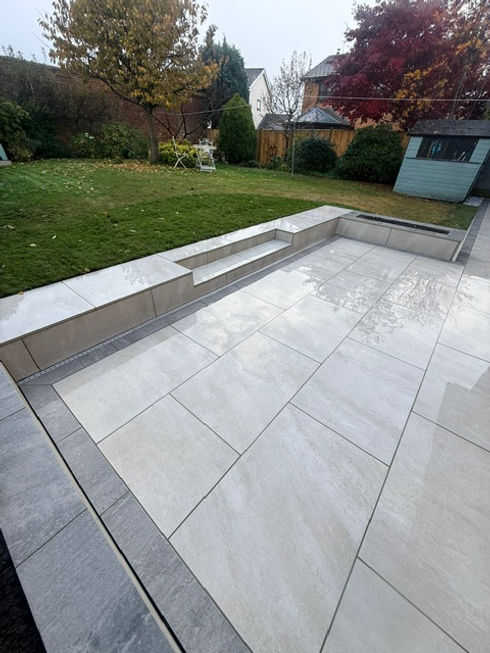 Light grey tiled patio with steps and green lawn