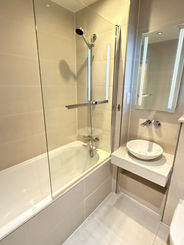 Modern bathroom with tub, glass shower screen, and sink