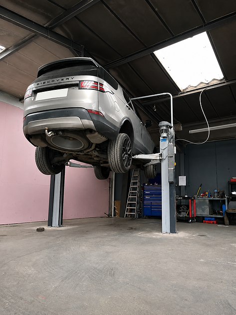 Silver SUV on a hydraulic lift for car servicing.